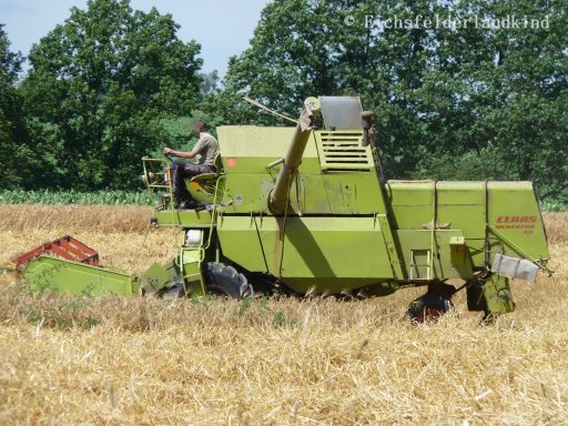 Erntewagen bei der Arbeit auf einem abgeernteten Feld mit einem Fahrer.